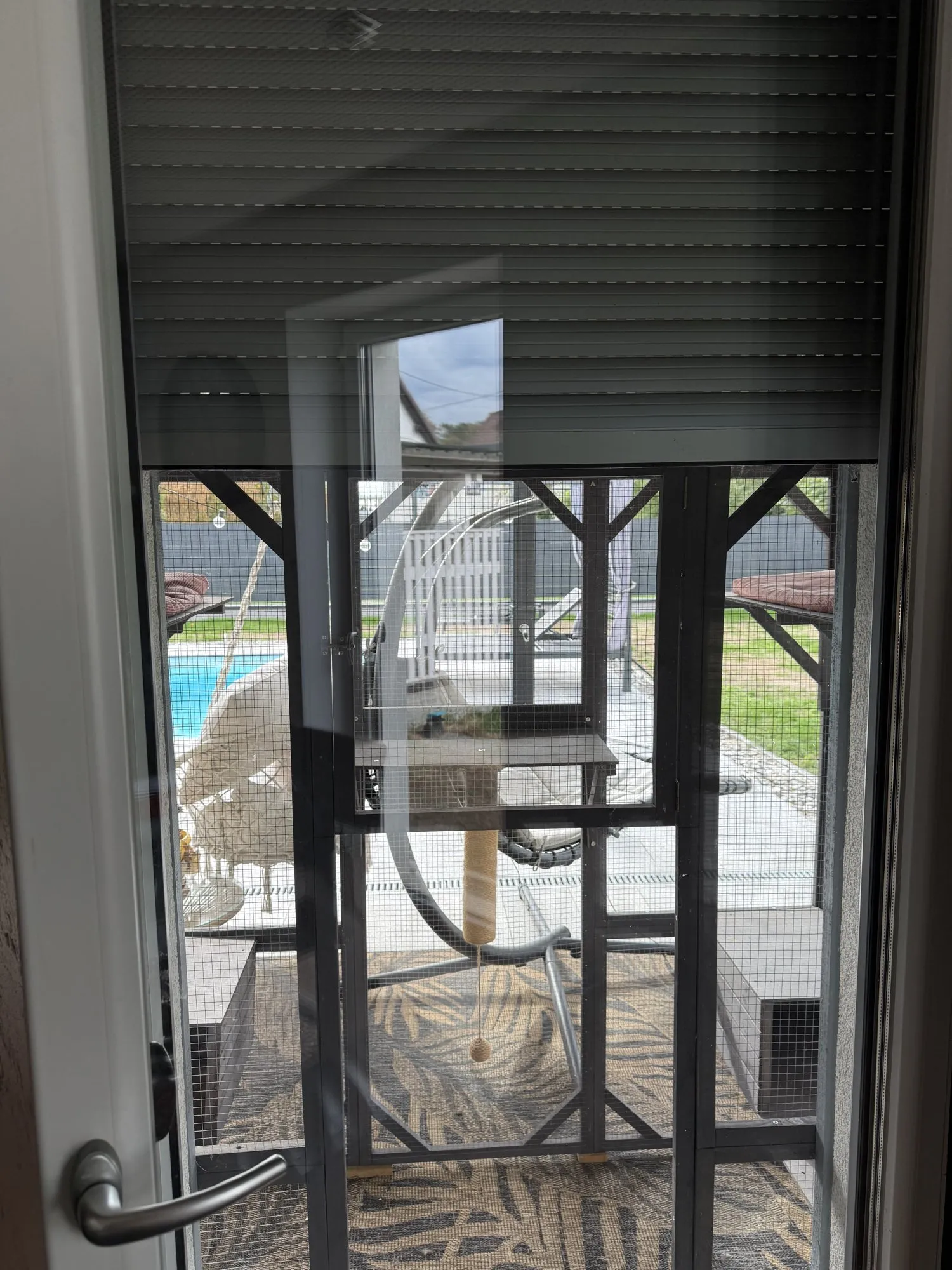 Esszimmertür mit halb geschlossenem Rollladen, dahinter das vergitterte Catio auf der Terrasse